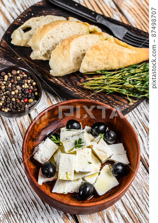 Antipasti platter with fresh feta cheese, bread and olives. White wooden background. Top view 87498707