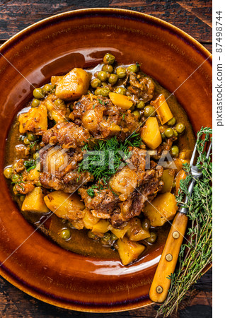 Beef veal oxtails stew with vegetables in a rustic plate. Dark wooden background. Top view 87498744
