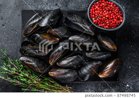 Boiled Mussels in shells on a marble board. Black background. Top view 87498745
