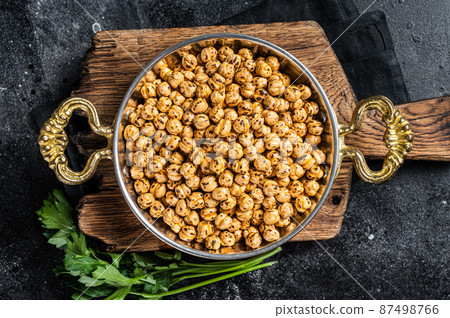 Fried chickpeas with turmeric, roasted spicy chickpeas or Indian chana or chole in a skillet. Black background. Top view 87498766