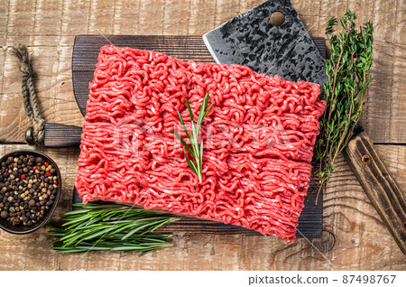 Fresh Raw mince beef meat on a butcher cutting board with cleaver. Wooden background. Top view 87498767