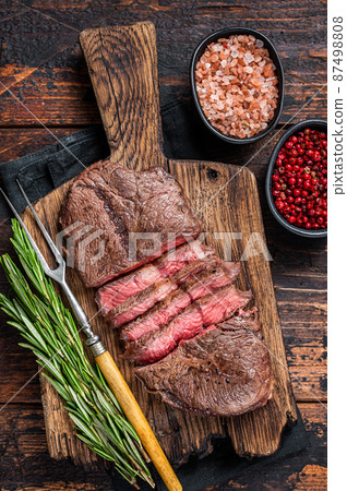 Fried Top Blade or flat iron roast beef meat steaks on wooden board with rosemary. Dark wooden background. Top View 87498808