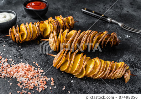 Roasted Tornado or twisted potatoes with ketchup sauce. Black background. Top view 87498856