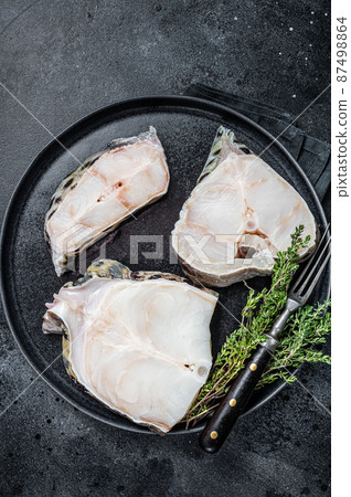 Fresh Raw wolffish o wolf fish Steak on a plate. Black background. Top view Fresh Raw wolffish o wolf fish Steak on a plate. Black background. Top view 87498864
