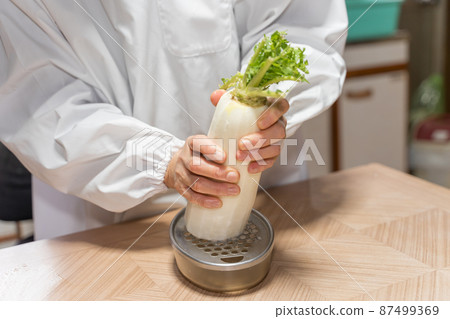 Senior woman making grated radish Senior woman making grated radish 87499369