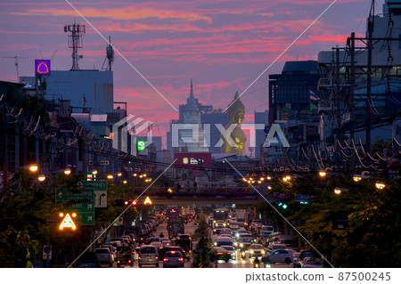 Aerial view of the Giant Golden Buddha in Wat Paknam Phasi Charoen Temple with cars on traffic street road in Phasi Charoen district, Bangkok. Urban town, Thailand. Downtown City. 87500245