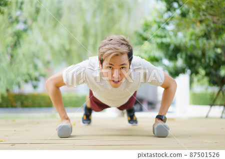 Active Asian sportsman making a body weight exercise, man doing push up workout with dumbbell. Intensive bodybuilding workout training. 87501526