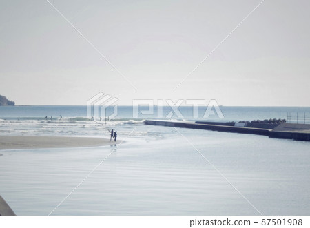 Two people playing in the sandbar with a surfer 87501908