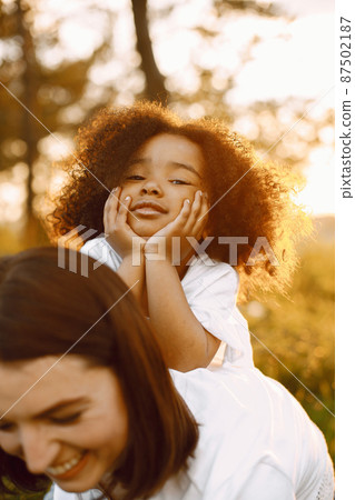 Caucasian mother holding her mixed race daughter on her back Caucasian mother holding her mixed race daughter on her back 87502187