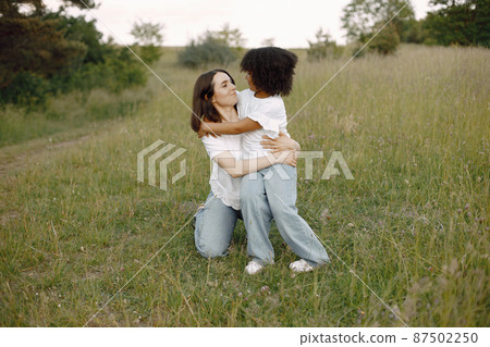 Caucasian mother embracing her mixed race daughter Caucasian mother embracing her mixed race daughter 87502250