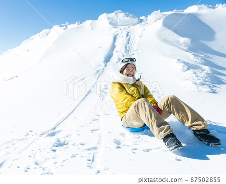 A woman enjoying sledding A woman enjoying sledding 87502855
