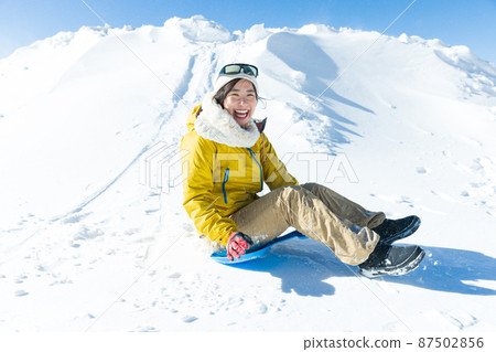 Cute woman enjoying sledding 87502856