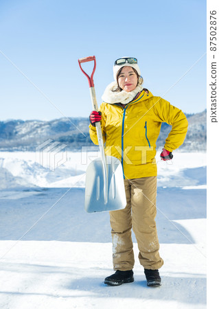 Woman standing with a shovel 87502876
