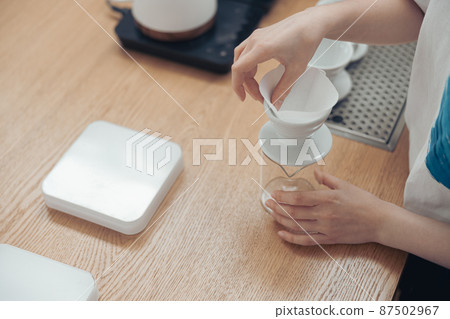 Female barista hands preparing coffee filter in cafeteria 87502967