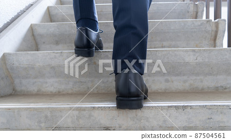 Image of a businessman climbing stairs 87504561
