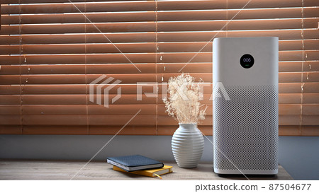 Air purifier in front of windows in living room for fresh air and healthy life. Air Pollution Concept. 87504677