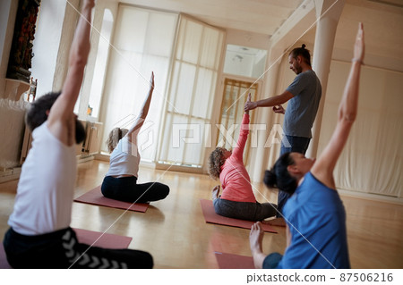 Live in happy harmony with life. Shot of a yoga instructor guiding one of his students. Live in happy harmony with life. Shot of a yoga instructor guiding one of his students. 87506216