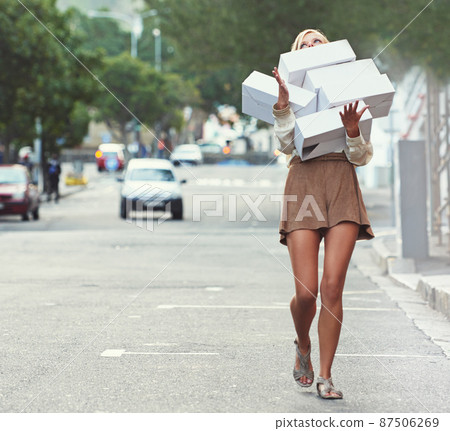 I think I might have overdid it.... A young woman walking down a street carrying shoe boxes. 87506269