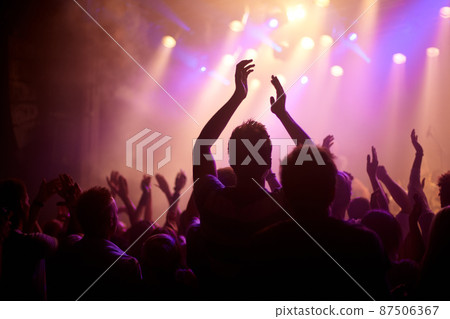 Rock on. Rear view of a music fan dancing with her arms raised at a music concert. 87506367