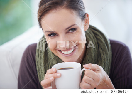 Enjoying the fresh aroma. A young woman smiling happily while holding a cup of coffee - closeup. Enjoying the fresh aroma. A young woman smiling happily while holding a cup of coffee - closeup. 87506474