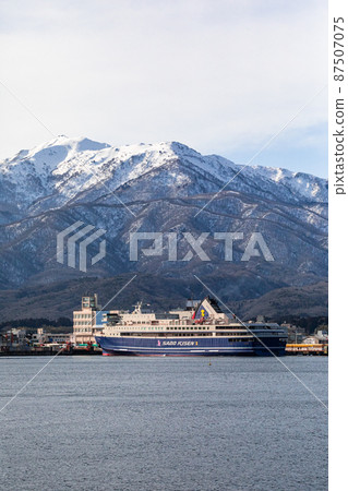 [Niigata Prefecture] Ryotsu Port and Osado Mountains in early spring welcoming passenger ships 87507075