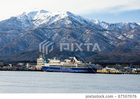 [Niigata Prefecture] Ryotsu Port and Osado Mountains in early spring welcoming passenger ships 87507076