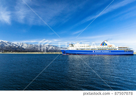 [Niigata Prefecture] Ryotsu Port and Osado Mountains in early spring welcoming passenger ships 87507078