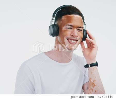 Where words fail, music speaks. Portrait shot of a handsome young man with vitiligo listening to music with wireless headphone on a white background. Where words fail, music speaks. Portrait shot of a handsome young man with vitiligo listening to music with wireless headphone on a white background. 87507110