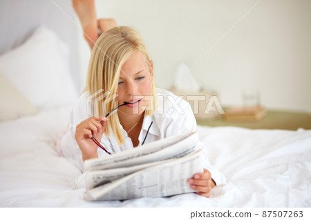 This article is very interesting. Young woman lying on the bed at home and reading the newspaper. This article is very interesting. Young woman lying on the bed at home and reading the newspaper. 87507263