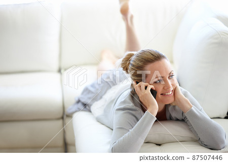 We could talk for hours. A happy young woman using her cellphone while casually lying on a couch. We could talk for hours. A happy young woman using her cellphone while casually lying on a couch. 87507446