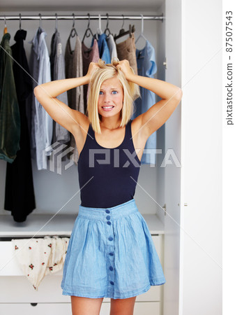 Her closets full, but she has nothing to wear. Frustrated young woman standing with her hands in her hair in front of her wardrobe. 87507543
