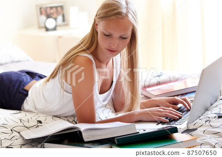 Trying to soak in all the information - Exams. Young college student working on an assignment at home. Trying to soak in all the information - Exams. Young college student working on an assignment at home. 87507650