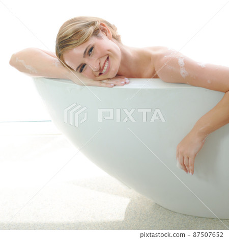 She enjoys pampering herself. A beautiful young woman smiling at you while enjoying a luxurious bath. She enjoys pampering herself. A beautiful young woman smiling at you while enjoying a luxurious bath. 87507652