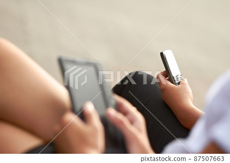 Modern technology. Cropped image of two students, one with a digital tablet and one with a cellphone. Modern technology. Cropped image of two students, one with a digital tablet and one with a cellphone. 87507663