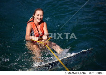 A pretty young woman in the water with a wakeboard wearing a lifejacket. A pretty young woman in the water with a wakeboard wearing a lifejacket. 87508080