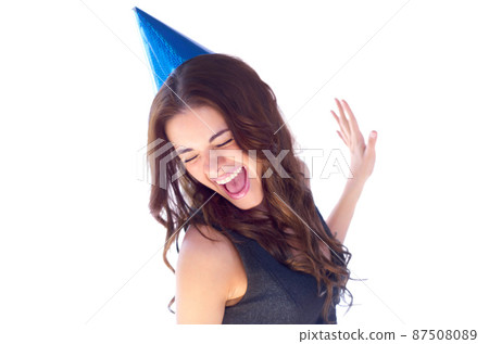 Shes a party girl. An attractive young woman dancing while wearing a party hat. Shes a party girl. An attractive young woman dancing while wearing a party hat. 87508089