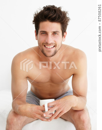 Enjoying the perfect cup of coffee. Portrait of a handsome male sitting in his underwear drinking a cup of coffeetea. Enjoying the perfect cup of coffee. Portrait of a handsome male sitting in his underwear drinking a cup of coffeetea. 87508261
