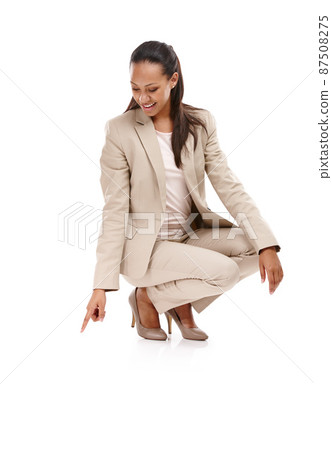 Nowhere to go but up. Full length shot of an attractive young woman in a suit crouching down and pointing towards the ground isolated on white. Nowhere to go but up. Full length shot of an attractive young woman in a suit crouching down and pointing towards the ground isolated on white. 87508275