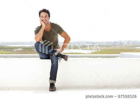 Casual and carefree. Portrait of a handsome young man looking thoughtful while sitting outside. 87508326