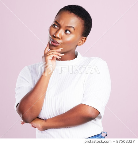 Let me think about it. Studio shot of a young woman looking thoughtful against a pink background. 87508327
