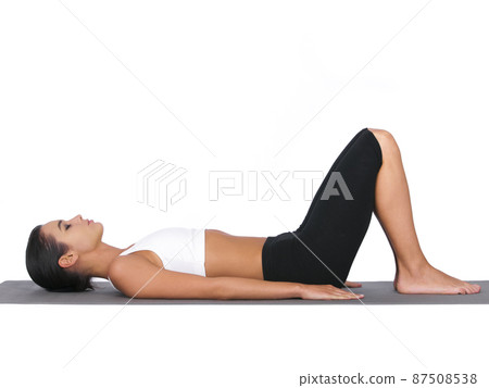 Breathing in deeply. A young woman doing stretches while isolated on white. 87508538