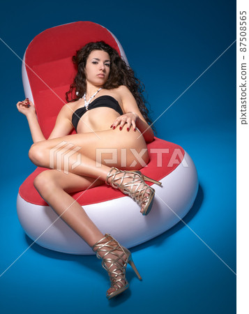 Lets get comfy. Portrait of a sexy woman posing provocatively on a designer chair. Lets get comfy. Portrait of a sexy woman posing provocatively on a designer chair. 87508565