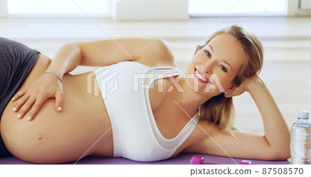 My baby will be well taken care of. Cropped portrait of an attractive young pregnant woman lying on her side on a yoga mat. 87508570