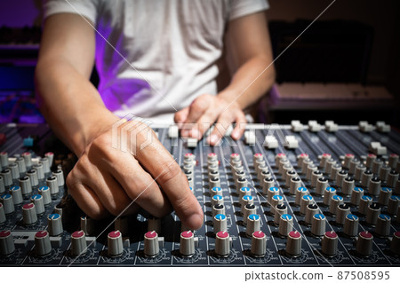 sound engineer hand adjusting eq knobs on audio mixing console. recording and broadcasting concept 87508595