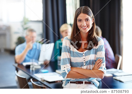 You create your own opportunities. Portrait of a beautiful woman with her colleagues blurred in the background. 87508793