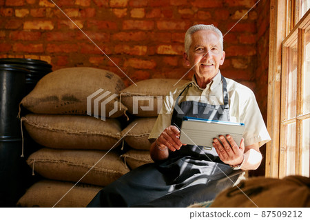 Getting some roasting tips online. Cropped portrait of a senior man using a tablet while working in a roastery. 87509212