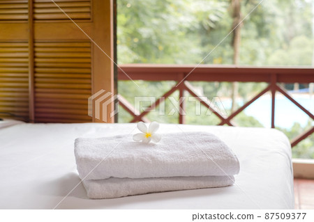 A hotel maid stacked towels on the bed and placed flowers on the towels in a hotel room A hotel maid stacked towels on the bed and placed flowers on the towels in a hotel room 87509377