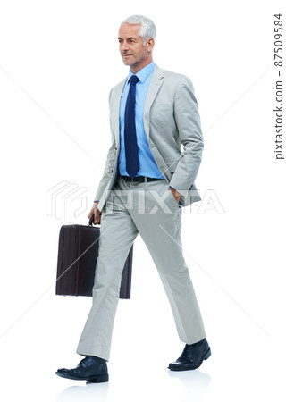 Hes got purpose in his stride. Full length studio shot of a mature businessman walking with a briefcase isolated on white. 87509584