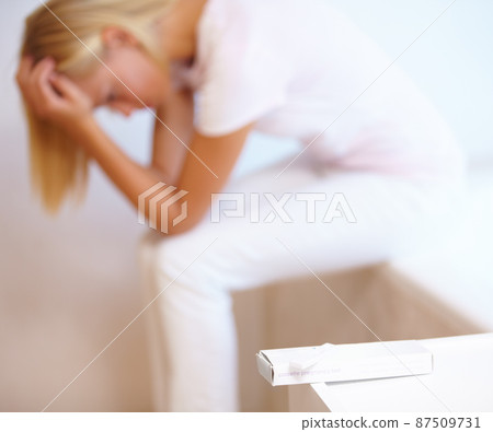 This unplanned pregnancy is weighing heavy on her mind. A young woman anxiously awaiting the results of her pregnancy test. 87509731