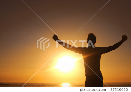 Breaking free from the rut. Silhouette of a man with his arms outstretched with the sunset in front of him. Breaking free from the rut. Silhouette of a man with his arms outstretched with the sunset in front of him. 87510030